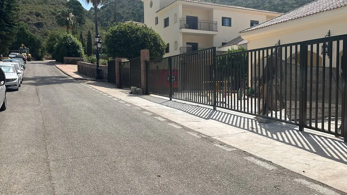 Cancela corredera de aluminio con valla de barrote vertical instalada en acceso a parcela en pendiente — METALISUR Málaga