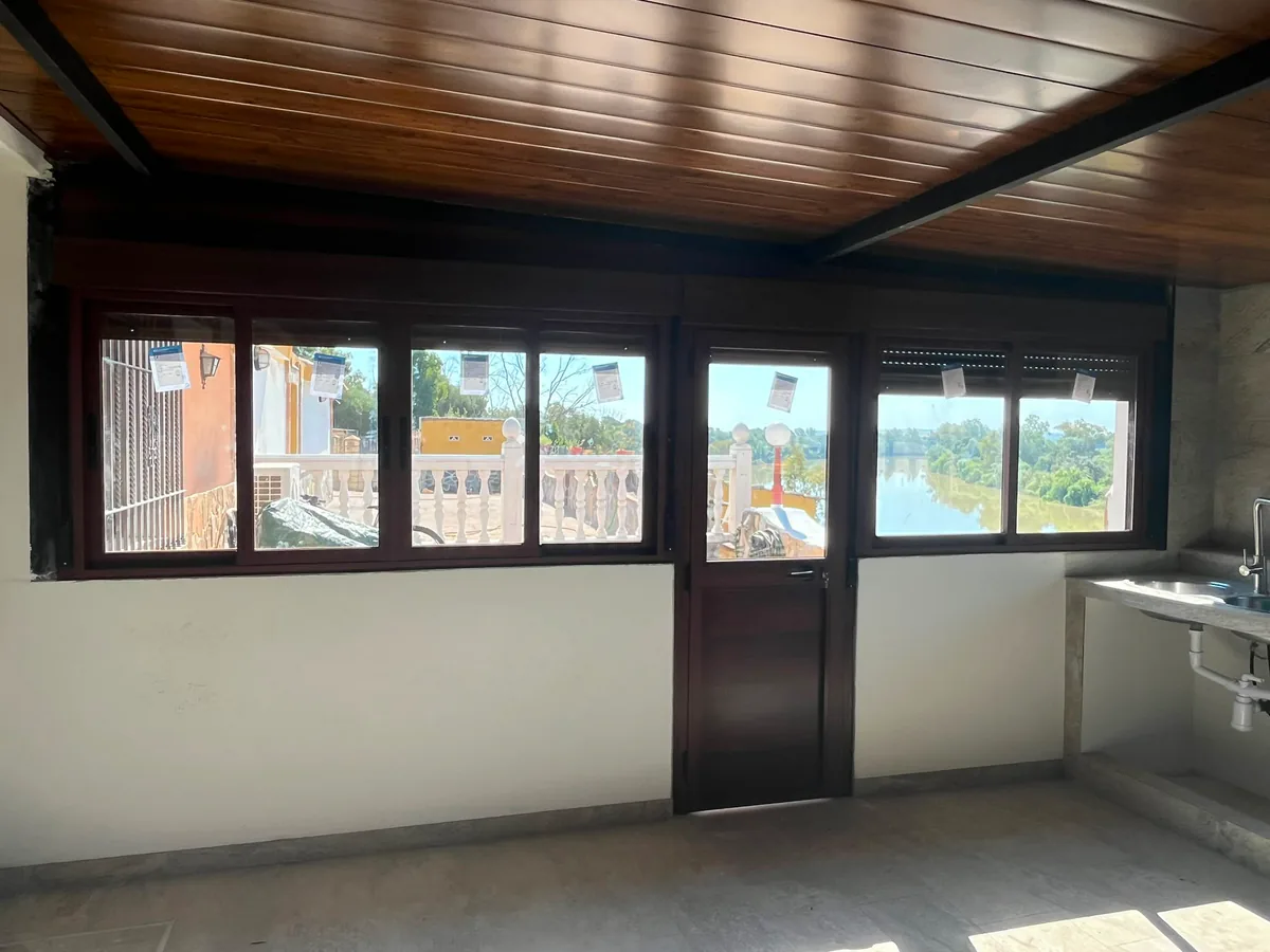 Puerta de aluminio con cristal integrada en conjunto de ventanas correderas imitación madera — METALISUR Málaga